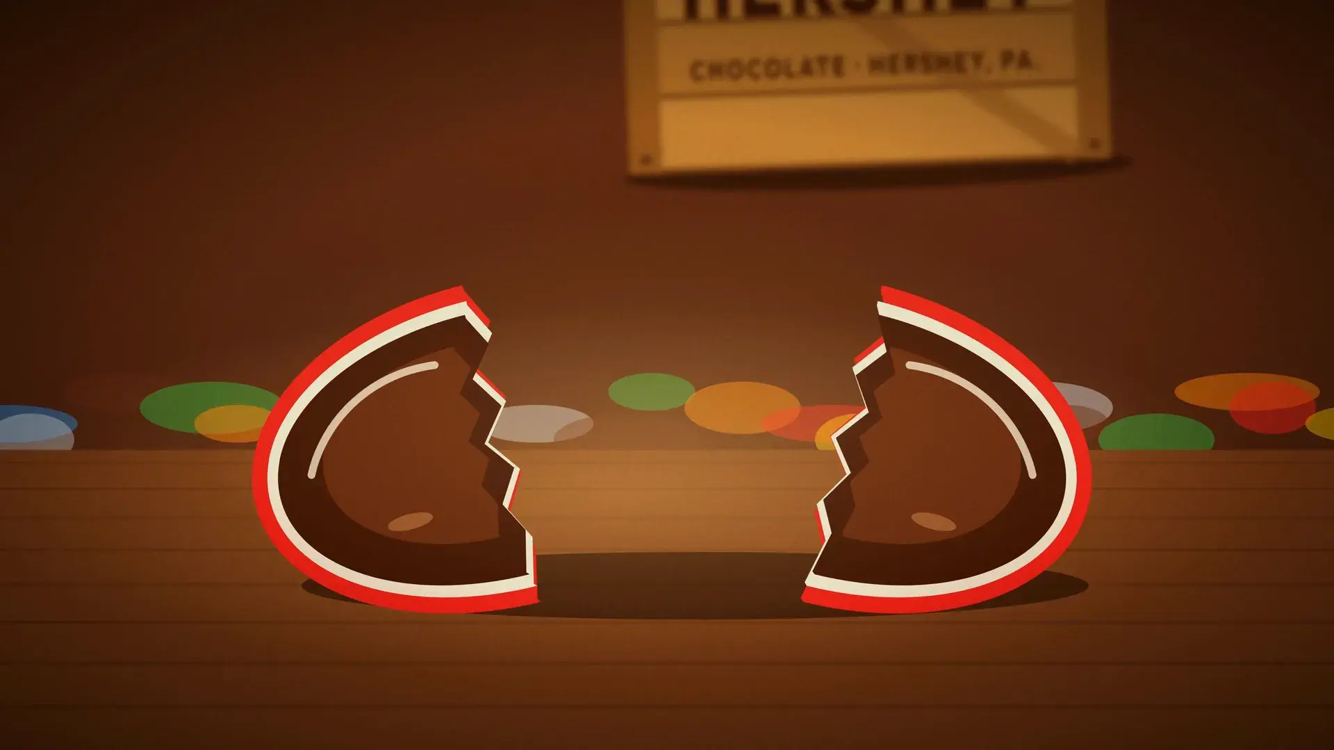 A red candy shell cracked open to show the chocolate inside.